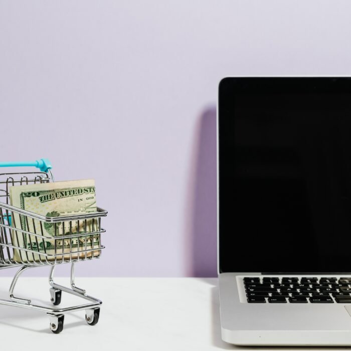 A shopping cart with money in it is next to a computer. Appropriately configured sales tools are required to close sales like this.